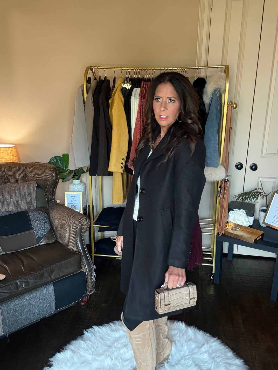 Side view of Janet wearing The Autumn Stroll Coat in Black with beige boots and a neutral handbag.