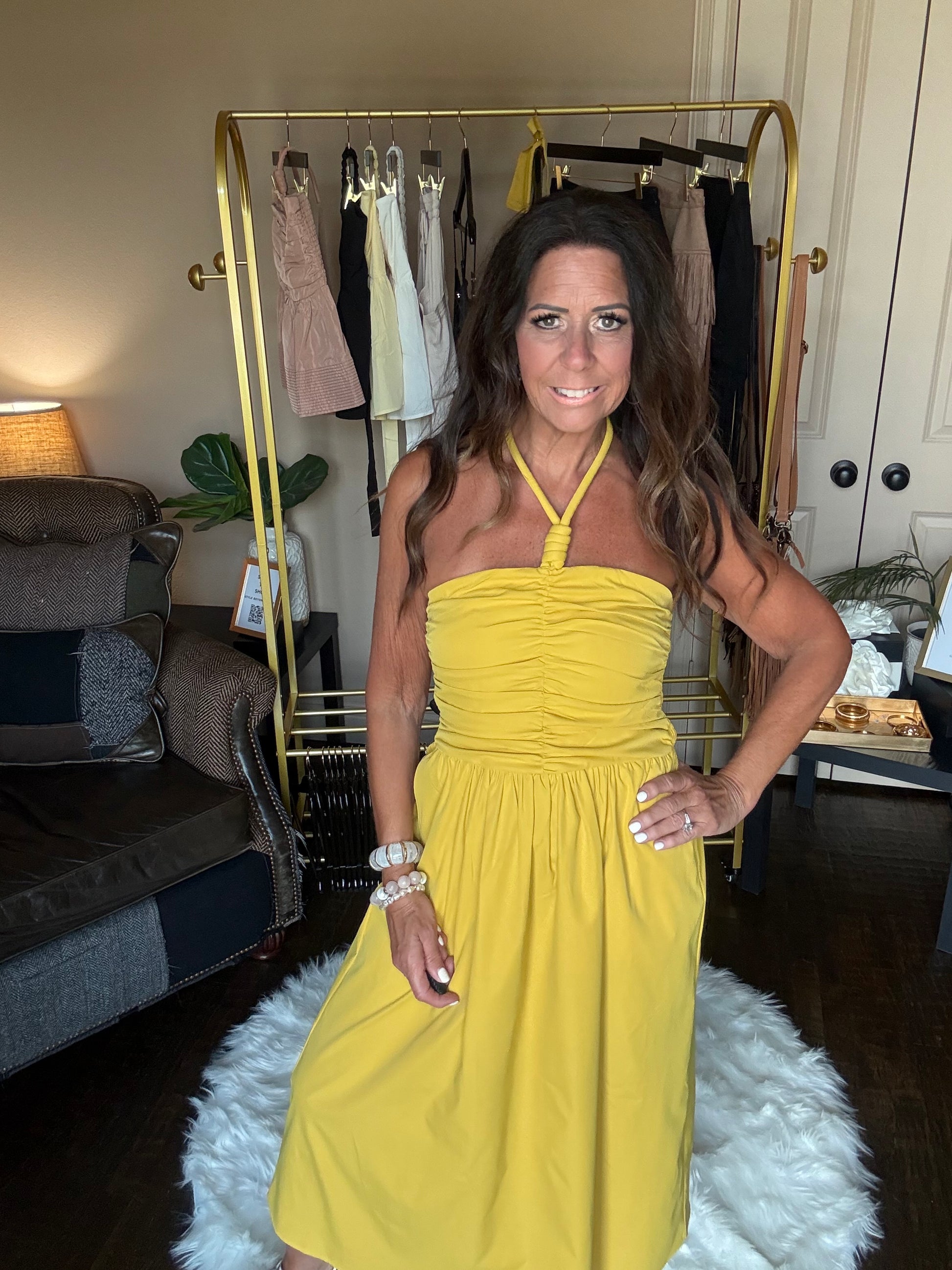 Woman in a yellow dress standing indoors with a neutral background