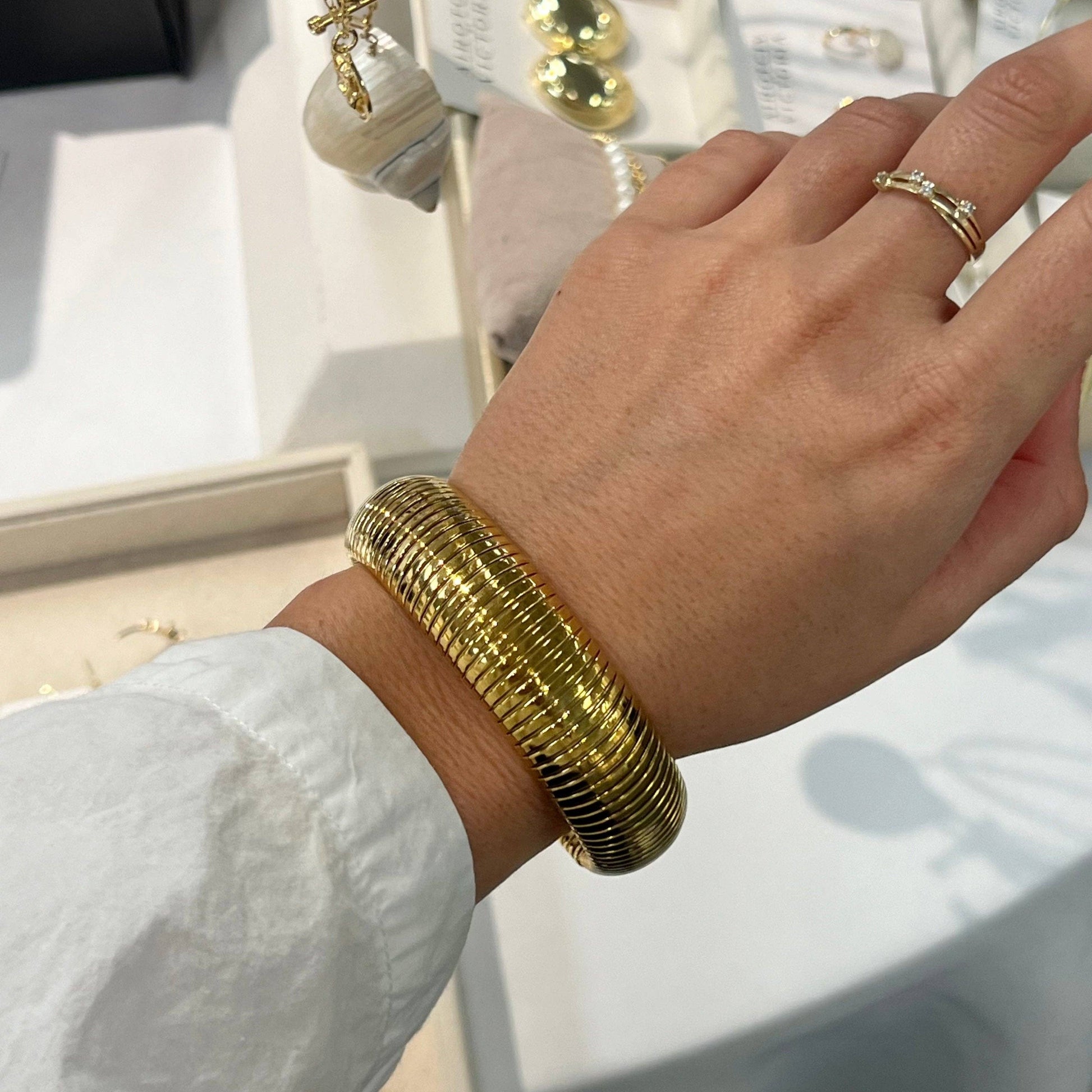 Gold bracelet on a wrist with a blurred jewelry store background