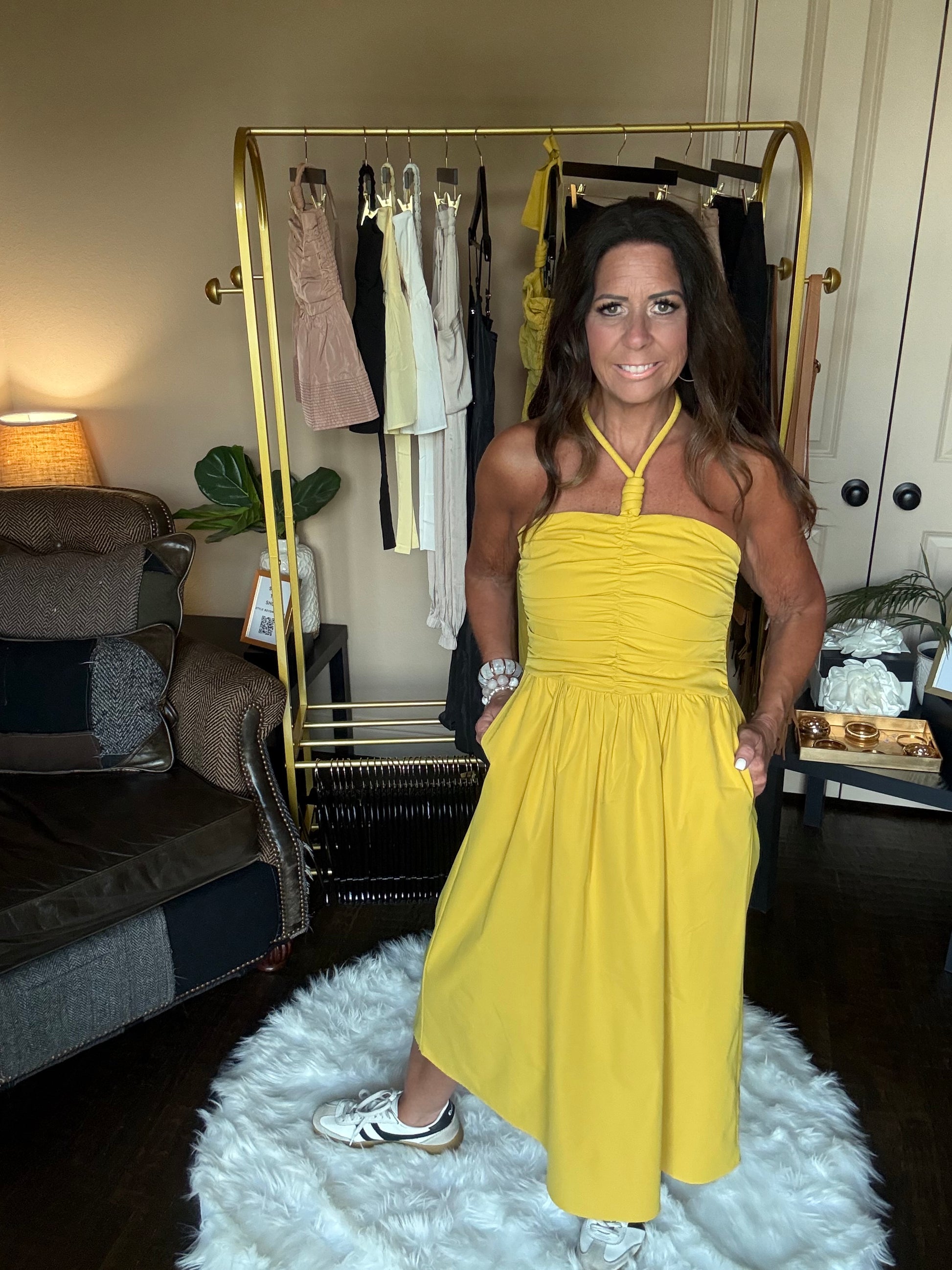 Woman in a yellow dress standing in a room with furniture and decor.