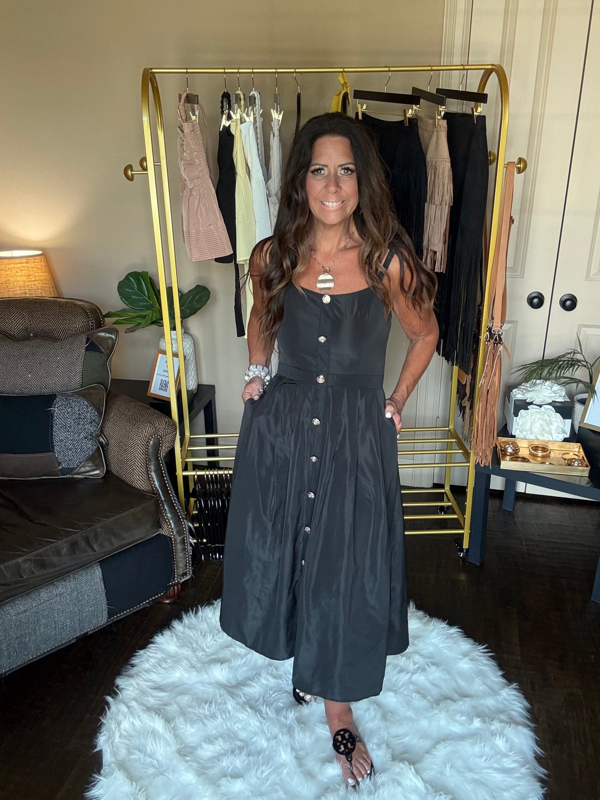 Woman in a black dress standing in front of a mirror at a boutique.