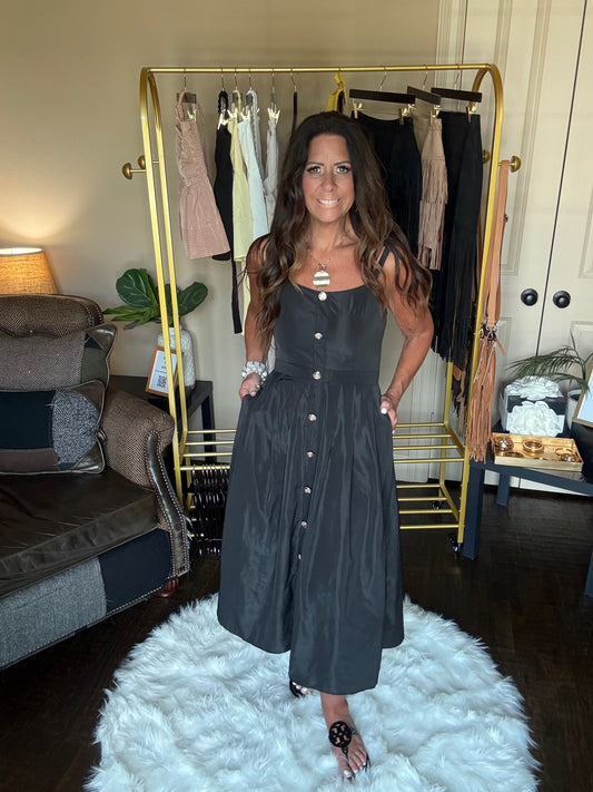 Woman in a black dress standing in front of a mirror at a boutique.