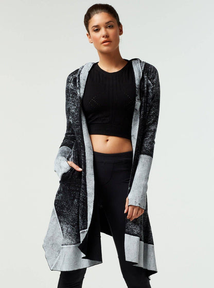 Woman wearing a long, patterned cardigan over a black outfit on a white background