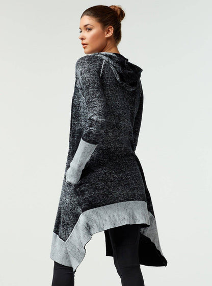 Woman wearing a long, dark gray cardigan with a light gray trim on a white background