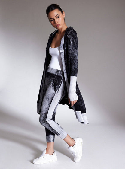 Woman wearing a stylish black and gray outfit with a white top on a gray background