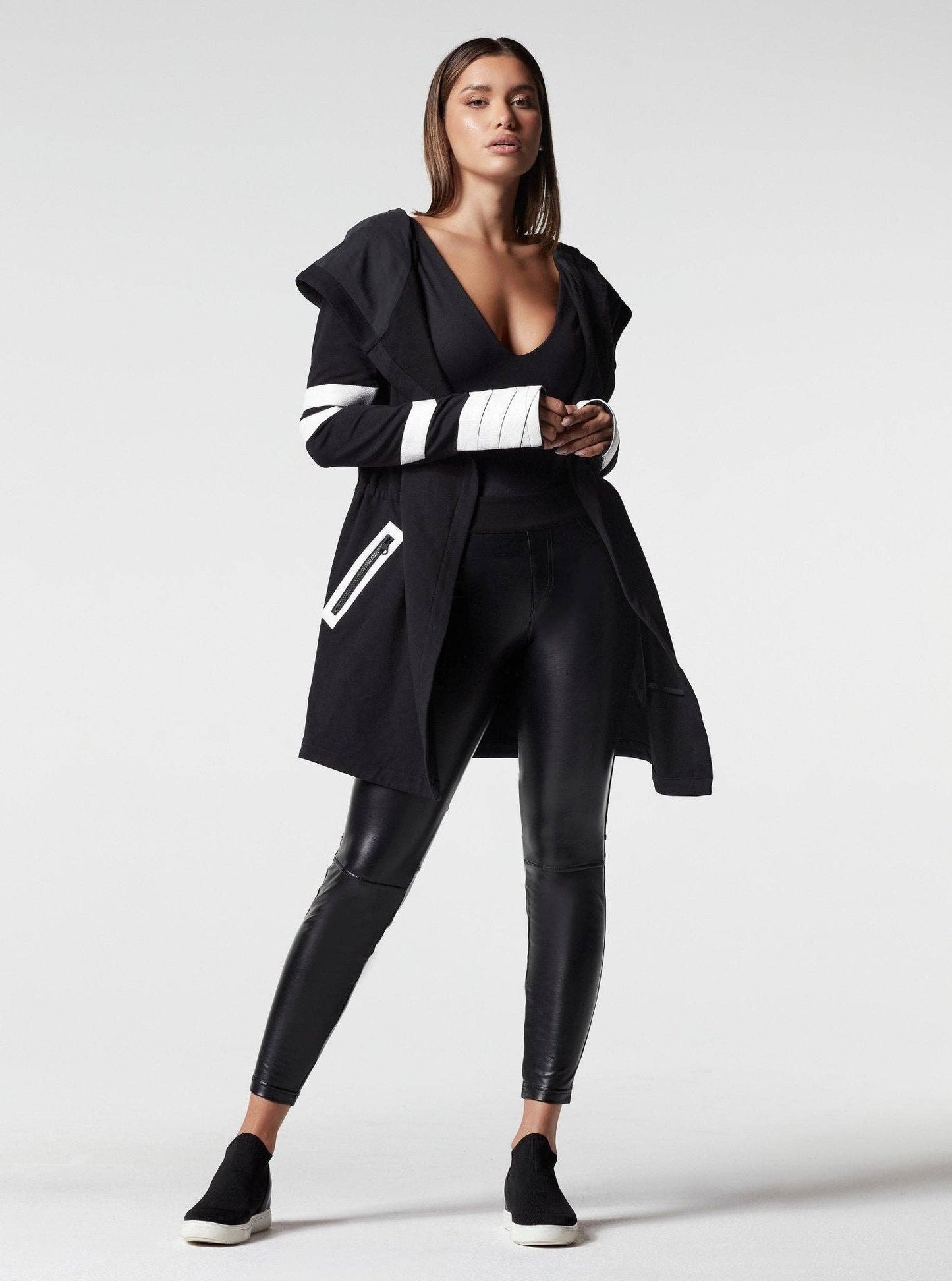 Woman wearing a black outfit with white accents on a white background