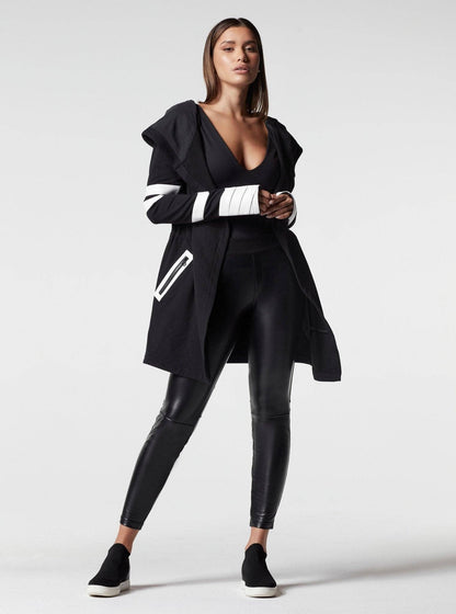 Woman wearing a black outfit with white accents on a white background