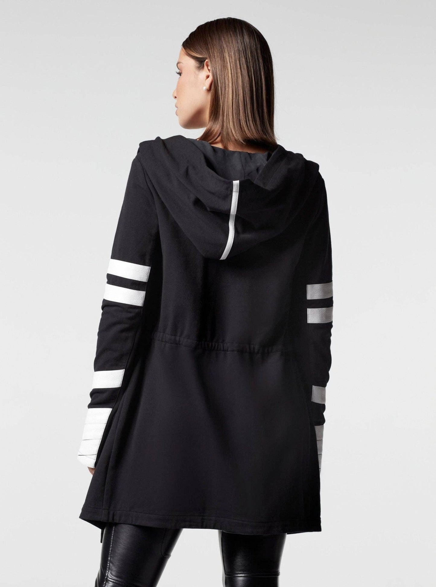 Black hooded jacket with white stripes on sleeves worn by a person on a light gray background