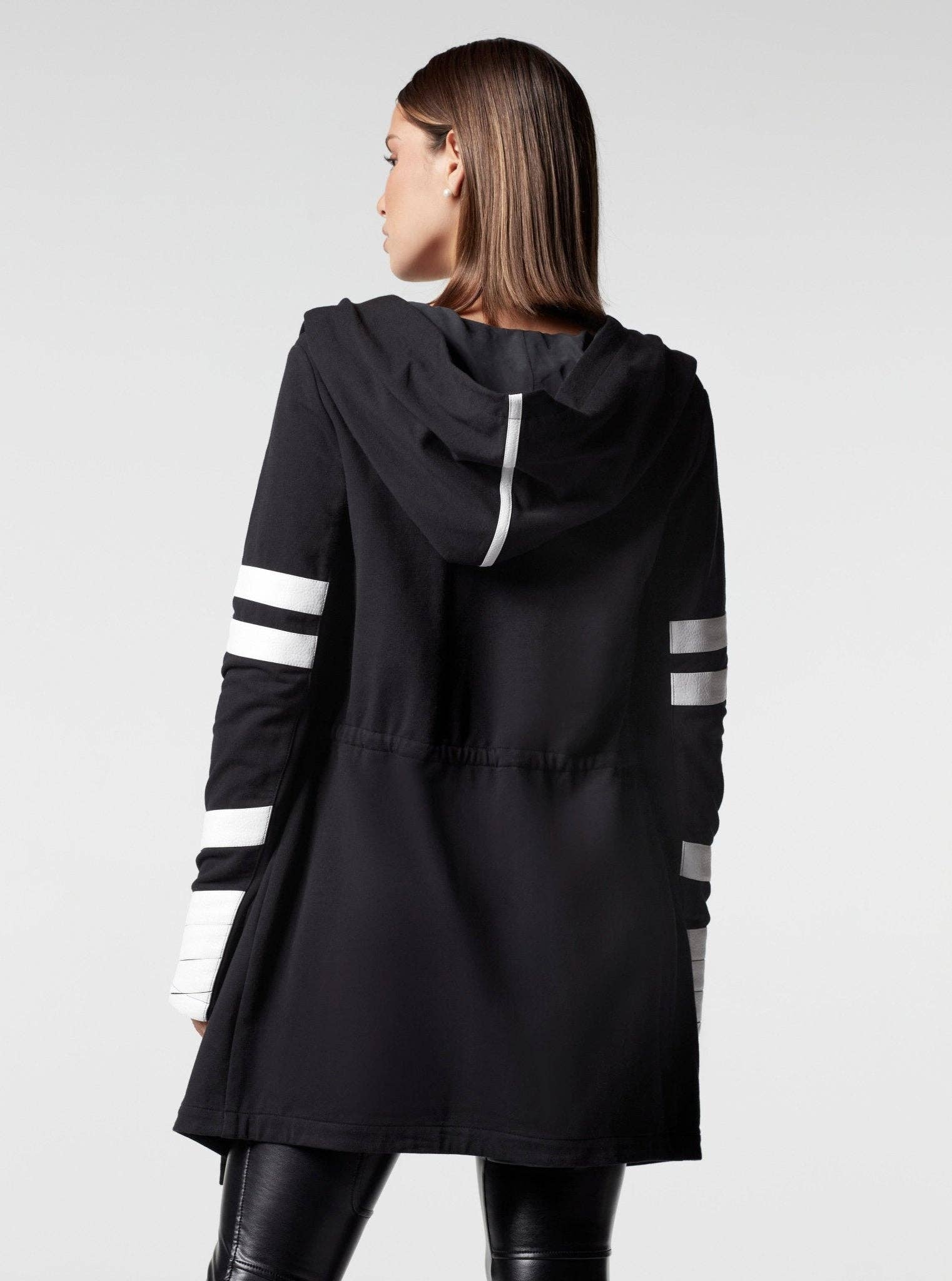 Black hooded jacket with white stripes on sleeves worn by a person on a light gray background