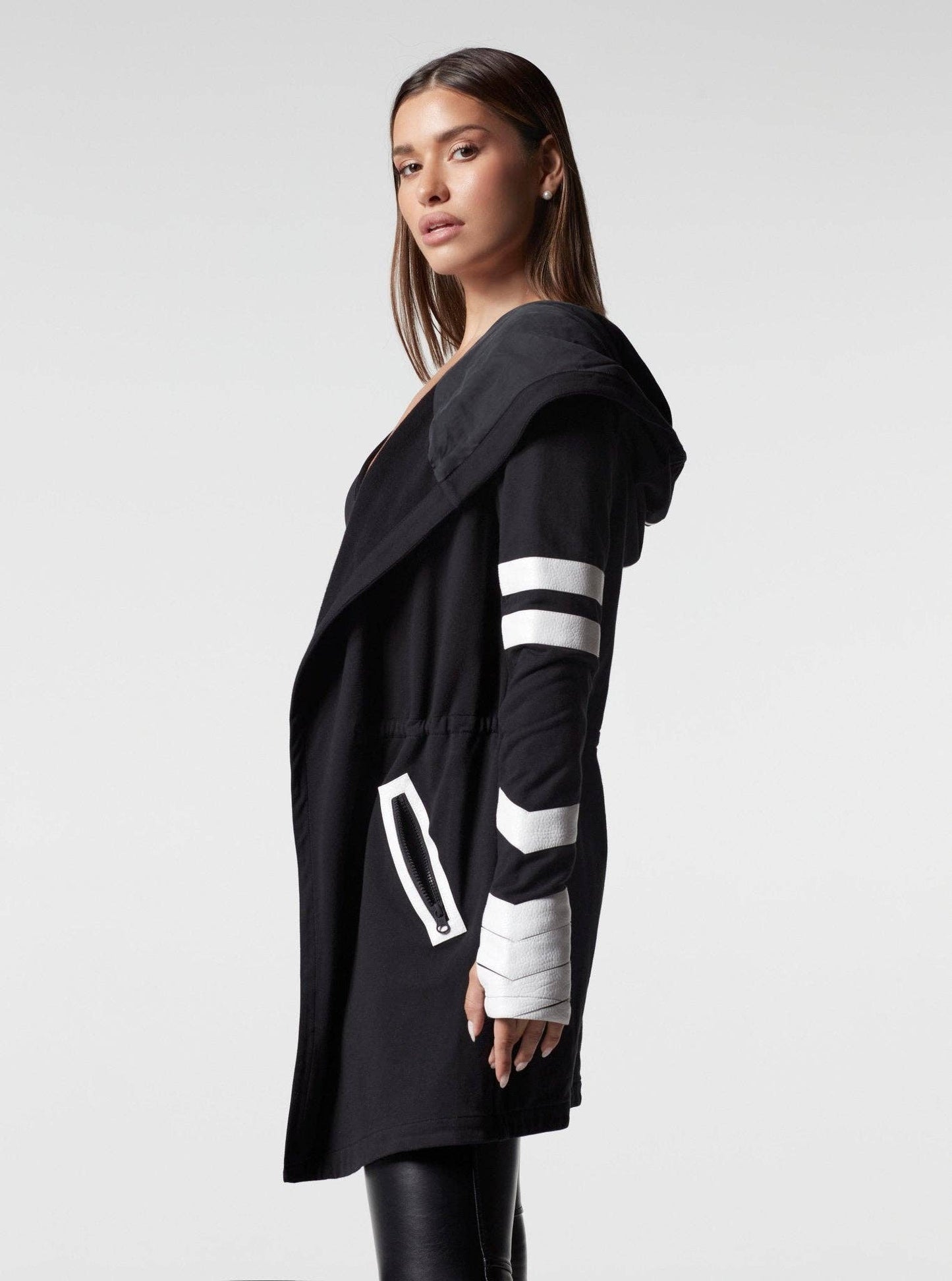 Woman wearing a black hooded jacket with white stripes on a white background