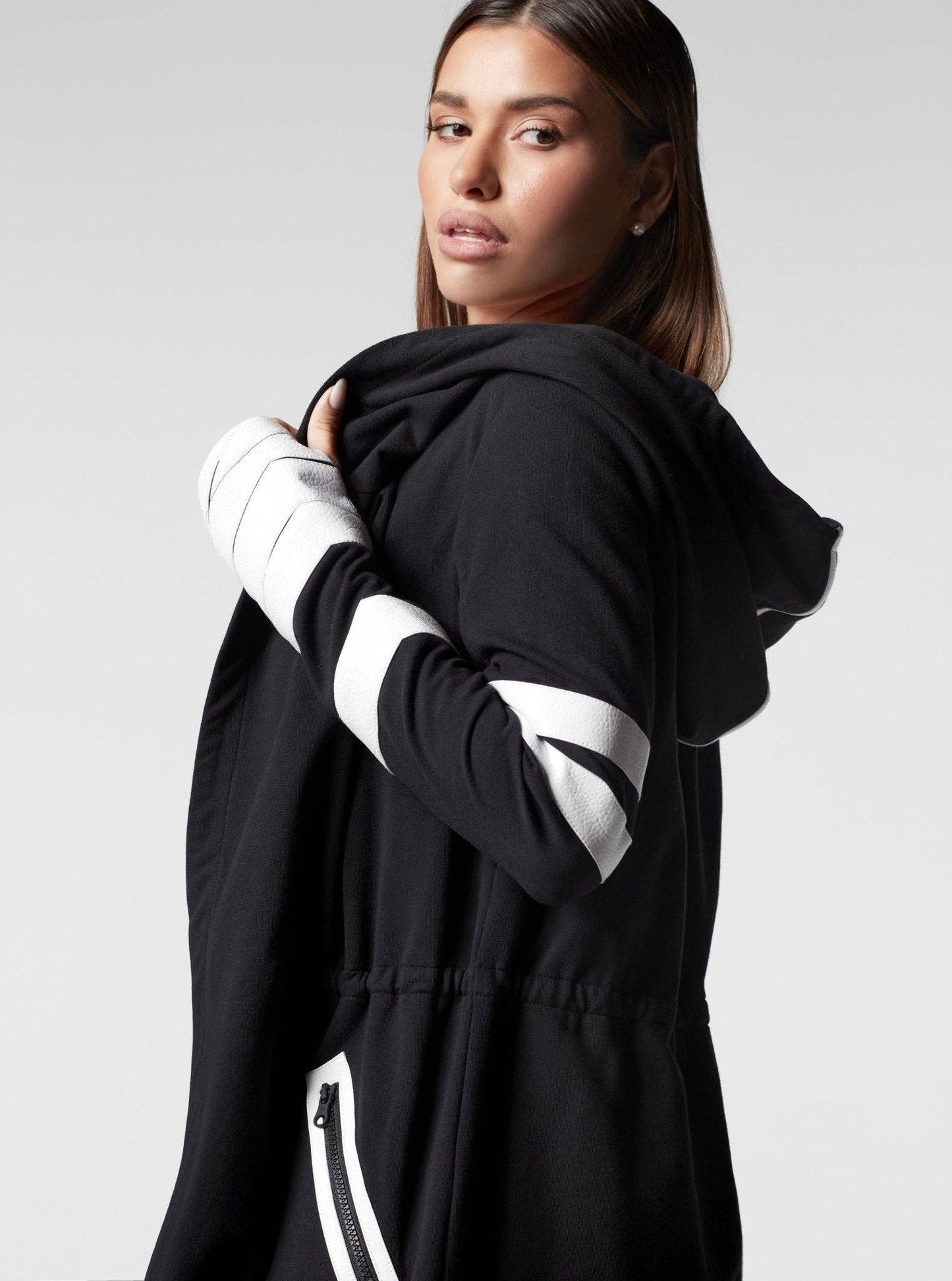 Person wearing a black hoodie with white accents on a plain background