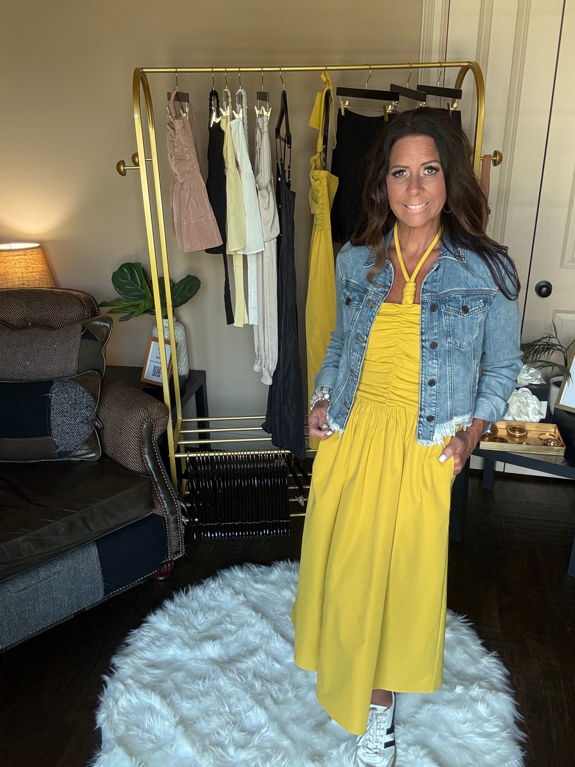 Woman in a yellow dress standing in front of a mirror with a gold frame.