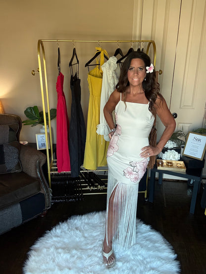 Woman in a white dress standing in a room with a clothing rack and furniture.