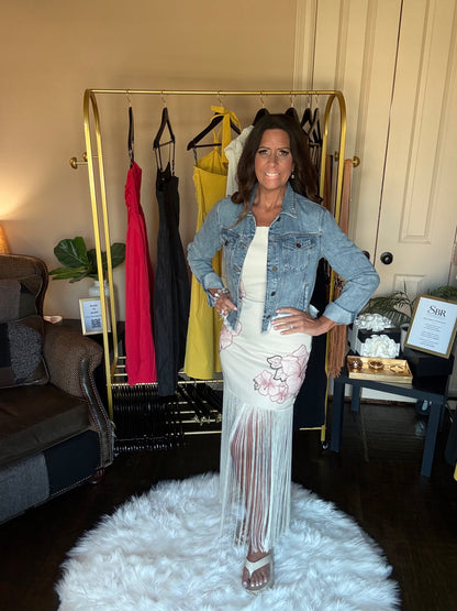 Woman posing in a room with a rack of dresses and a white rug.