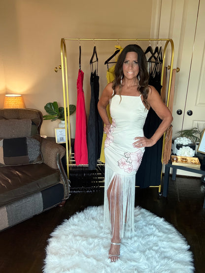 Woman in a white dress standing in a room with a rack of dresses and a couch.