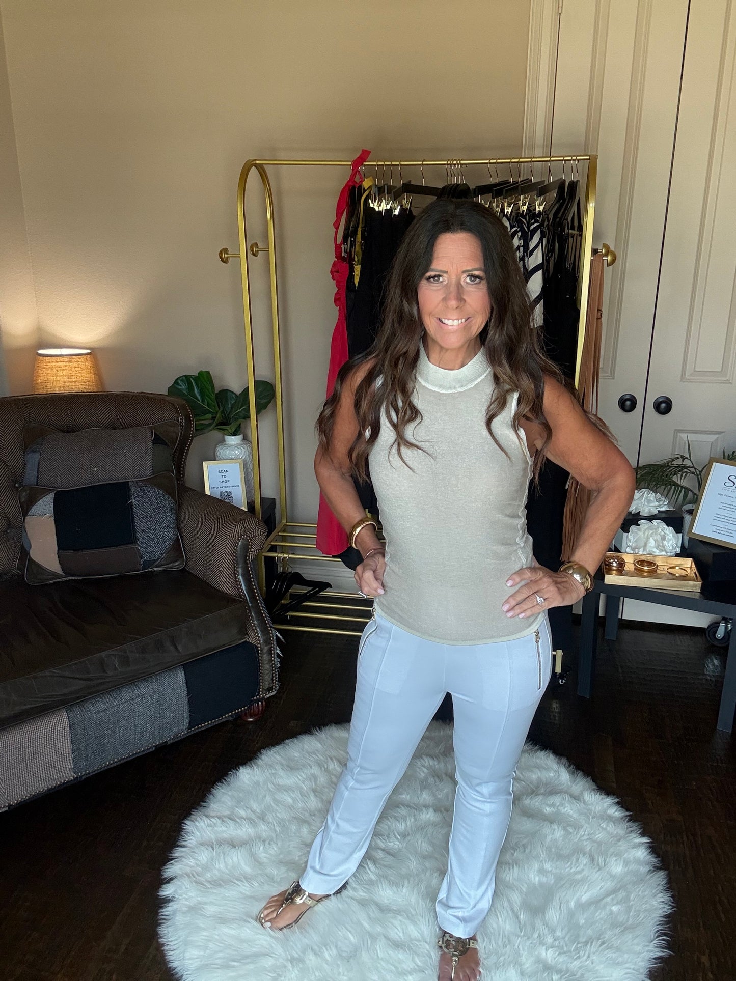 Woman sitting on a fluffy white rug in a room with a mirror and furniture.
