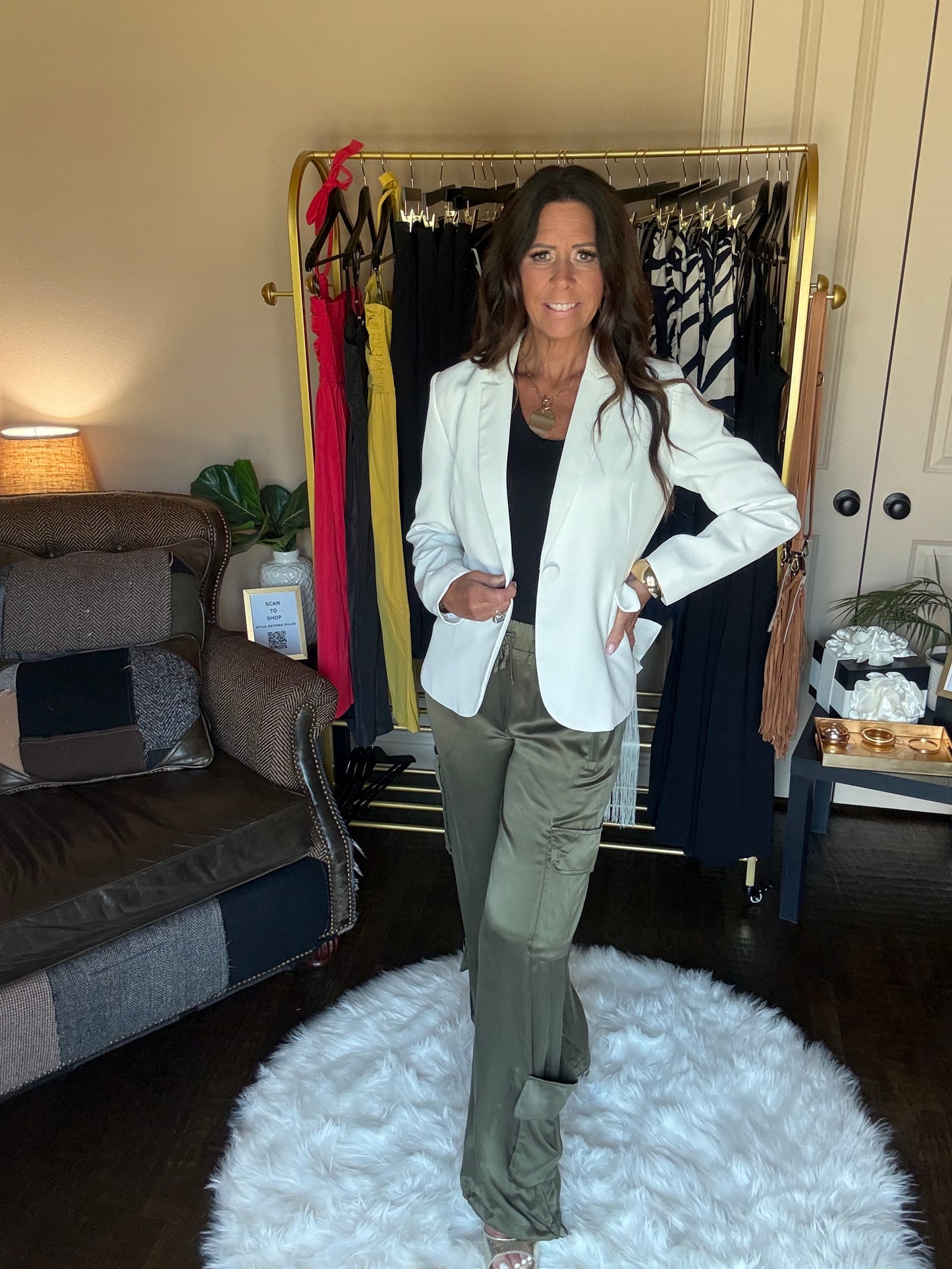 Woman standing in a room with a mirror reflecting her and a white textured wall.