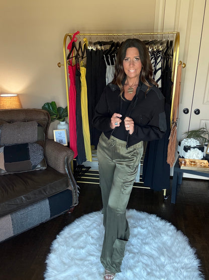 Person standing in front of a mirror with a rack of clothes and a suitcase on the floor.