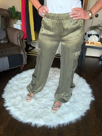 Person holding a pair of green pants on a white rug