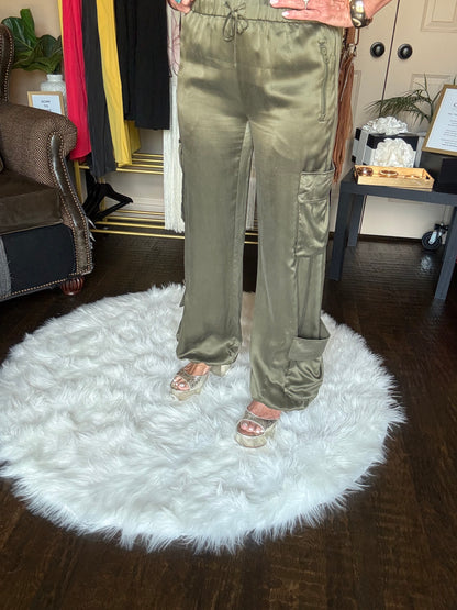 Person wearing green pants standing on a white fluffy rug in a room with furniture and decor.