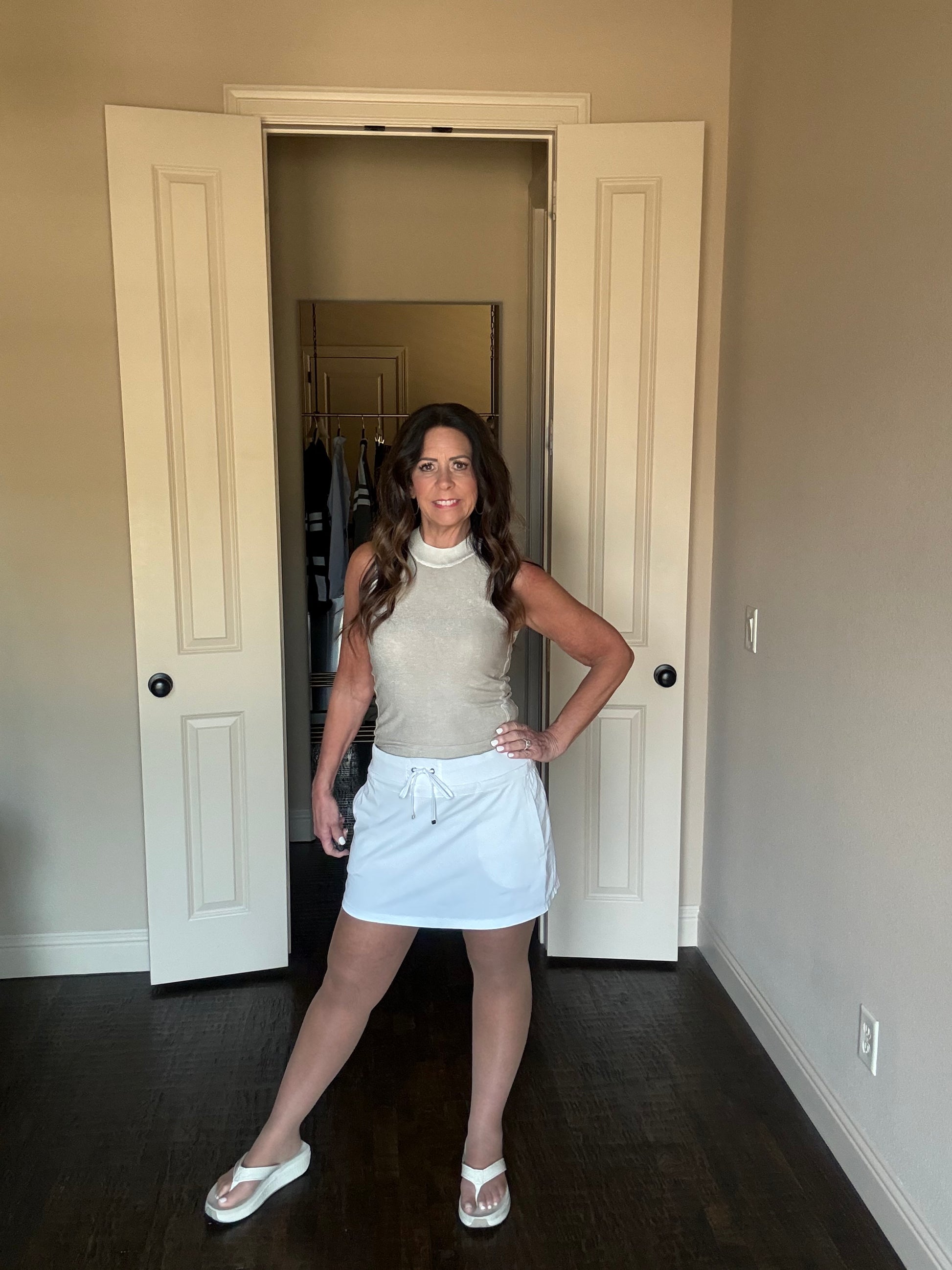 Woman standing in a room with open doors and neutral walls.
