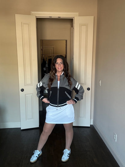 Woman posing in a room wearing a jacket and skirt