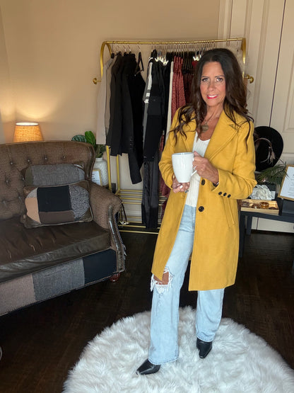 Model is wearing a yellow coat and jeans.