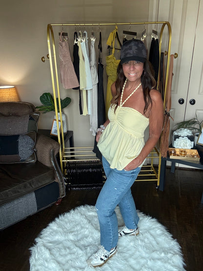 Person wearing a yellow top and blue jeans standing in a room with a gold bar cart and white rug.