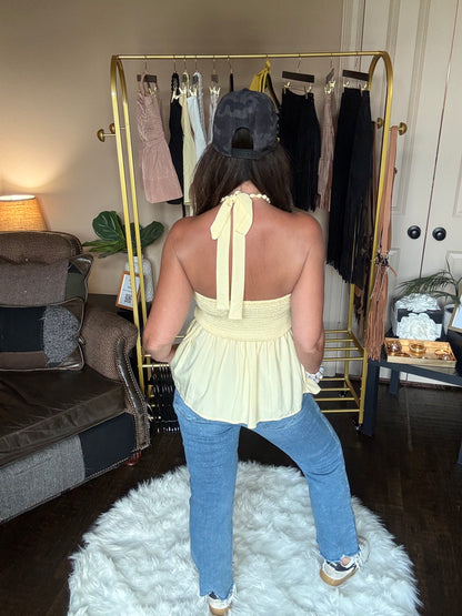 Person wearing a yellow dress and blue jeans standing in a room with furniture and decor.