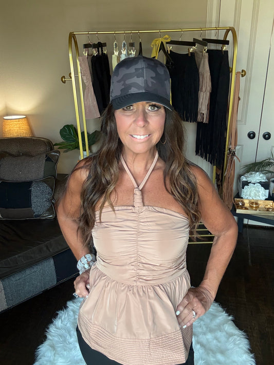 Woman in a beige top posing in a room with a mirror and decorative items.