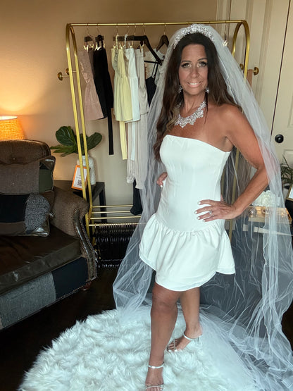 Woman in a white wedding dress with a veil standing in a room.