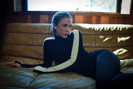 Person wearing a black and white outfit sitting on a leather couch.