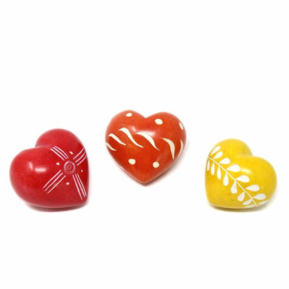 Three heart-shaped ceramic items in red, orange, and yellow with white patterns on a white background.