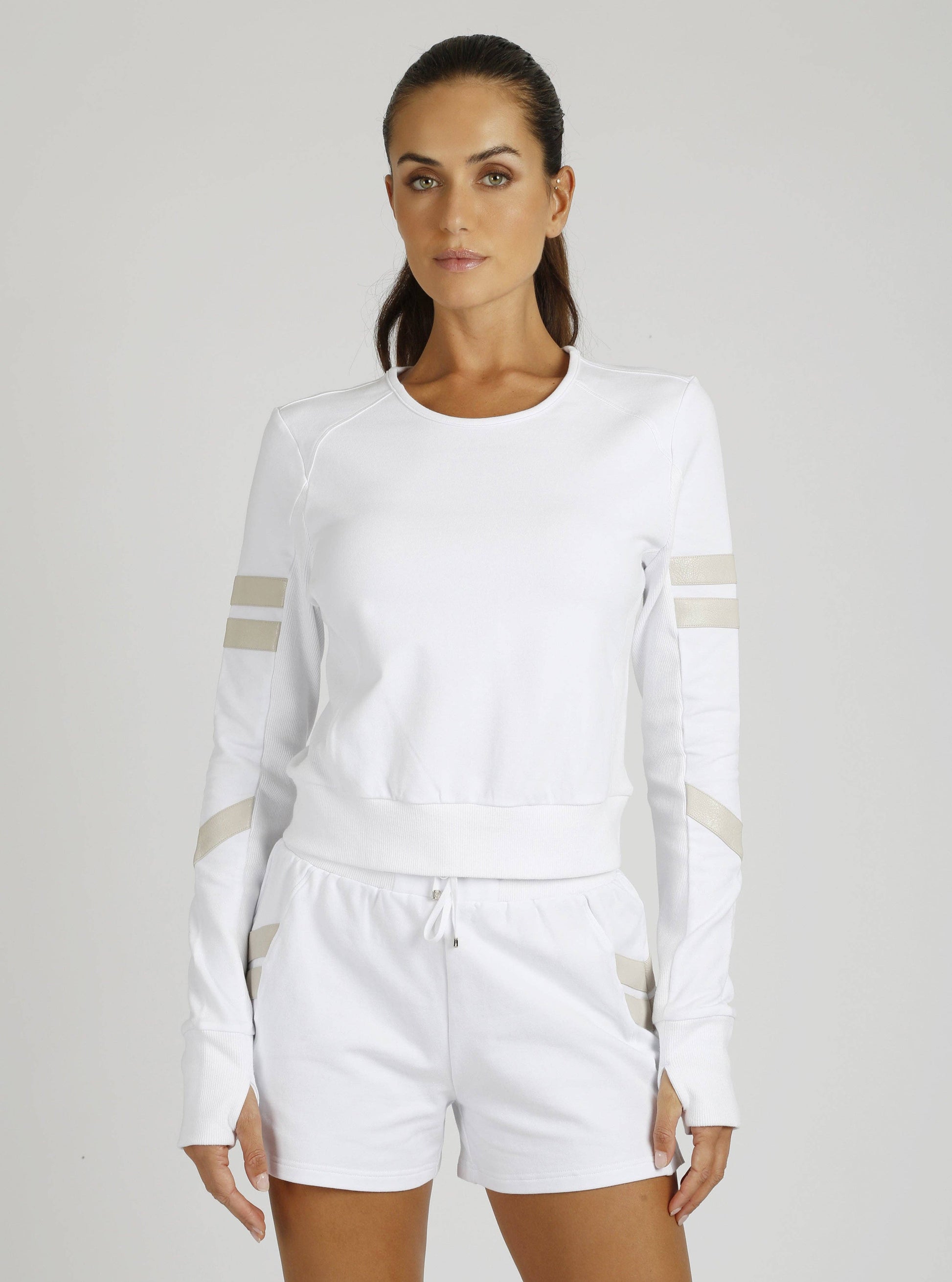 Woman wearing a white outfit with beige accents on a plain background