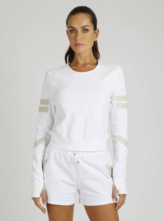 Woman wearing a white outfit with beige accents on a plain background
