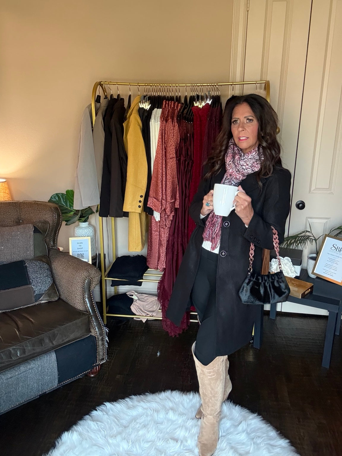 Janet wearing The Autumn Stroll Coat in Black with a patterned scarf and holding a coffee mug