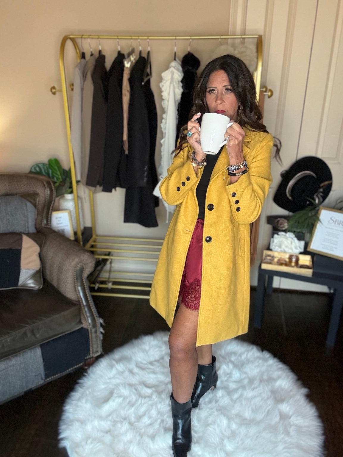 Angled view of the yellow Autumn Stroll Coat showing lapels, front pockets and button cuffs, worn with black ankle boots.