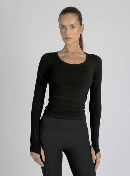 Woman wearing a black long-sleeve top and leggings on a gray background