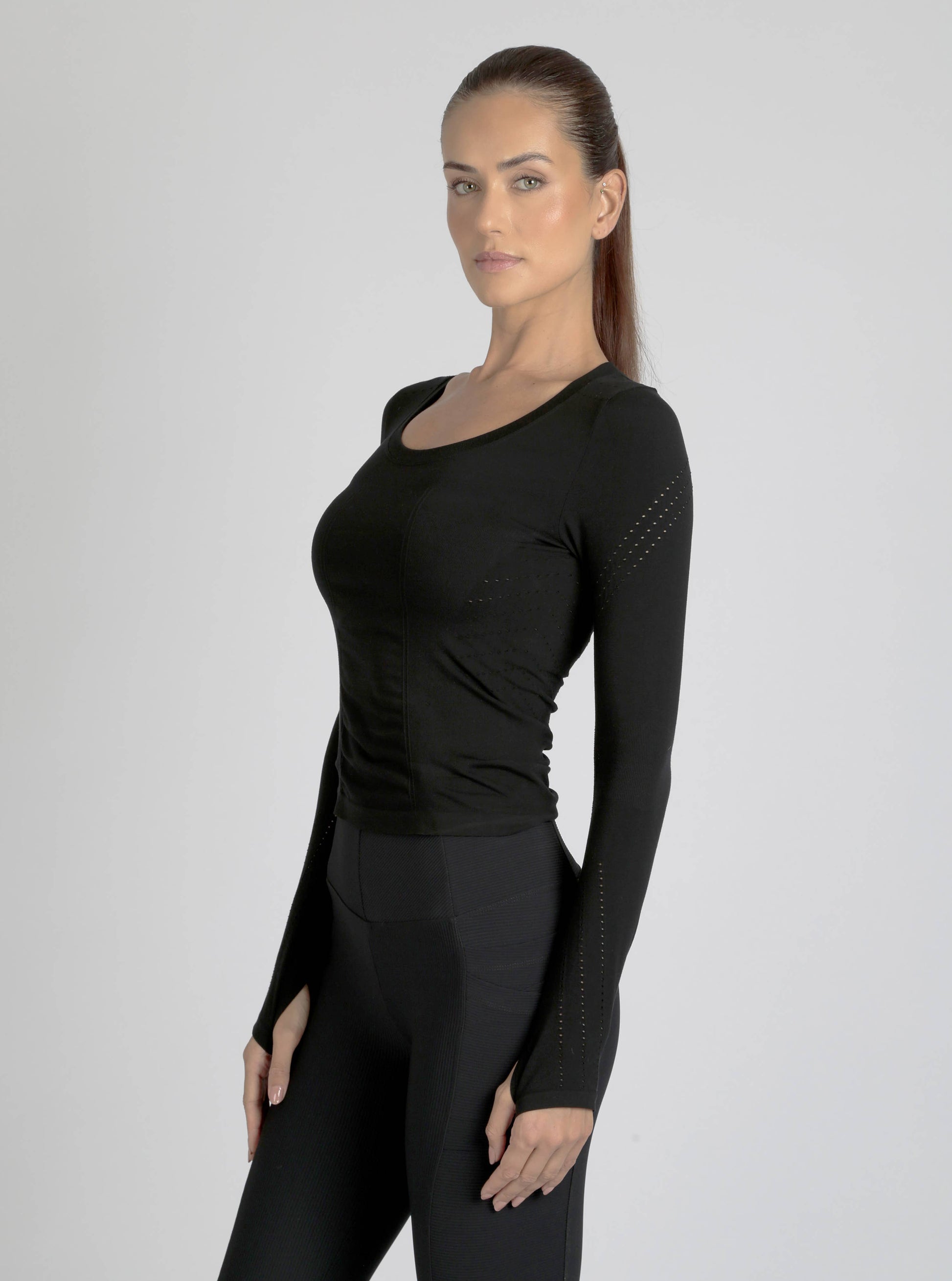 Woman wearing a black long-sleeve athletic top and leggings on a gray background