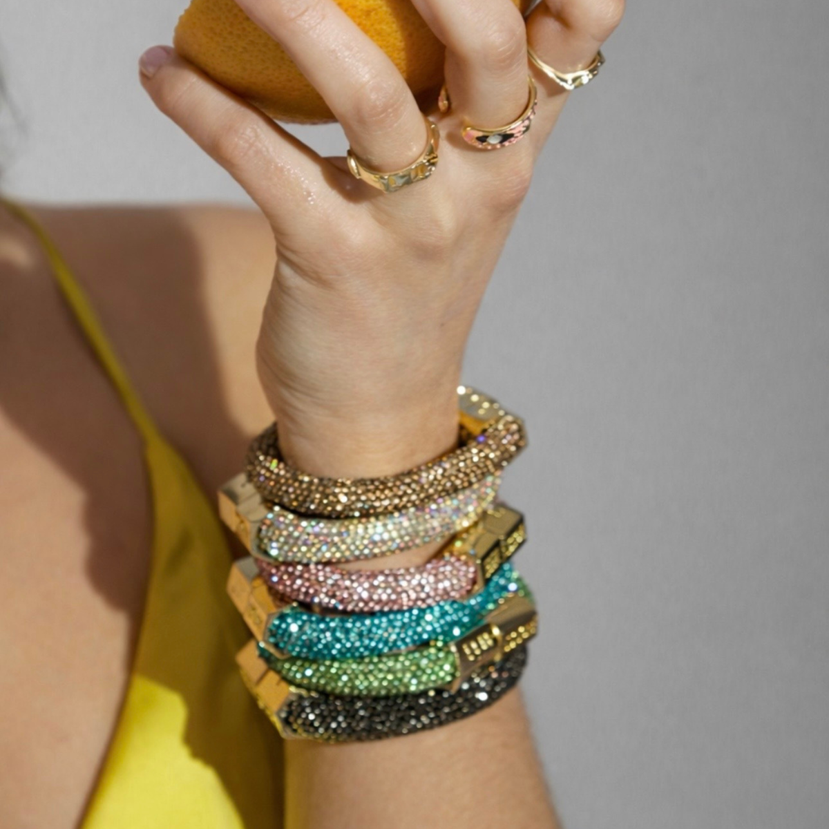 Holst + Lee Sparkle Bracelets in multiple crystal colors stacked on a wrist with gold clasps.