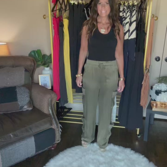 Person wearing green pants standing on a white fluffy rug in a room with furniture and decor.