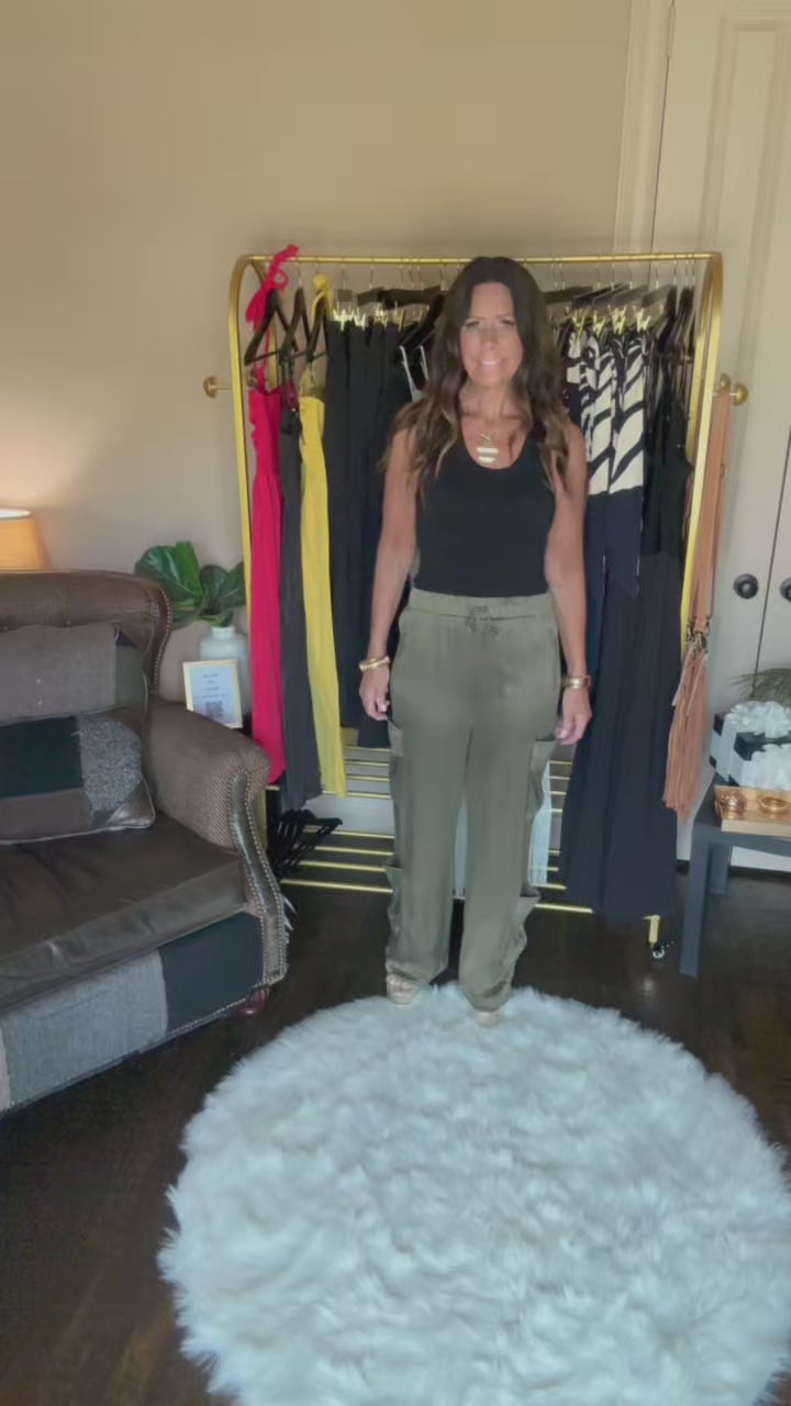 Person wearing green pants standing on a white fluffy rug in a room with furniture and decor.