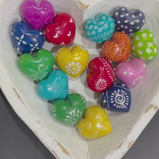 Hand holdng multicolor soapstone grateful hearts un a white heart-shaped bowl.