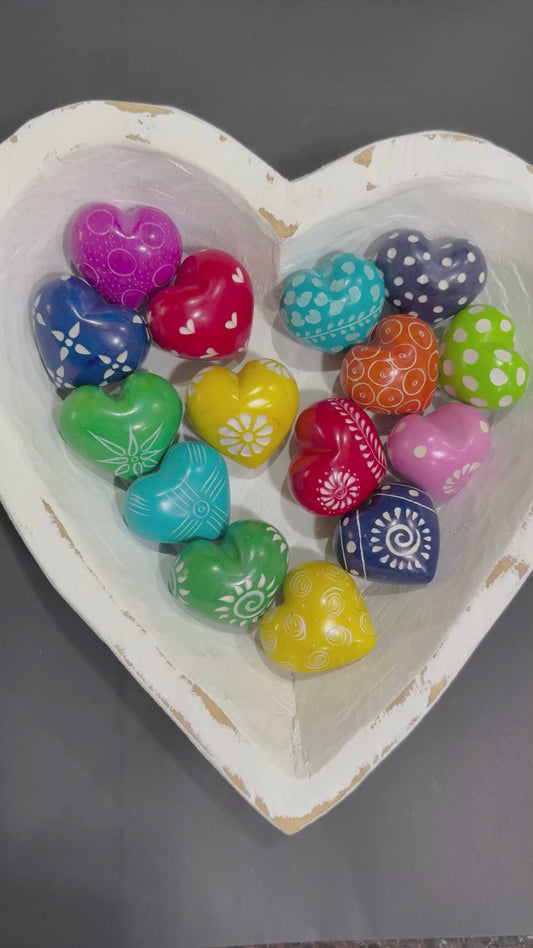 Hand holdng multicolor soapstone grateful hearts un a white heart-shaped bowl.