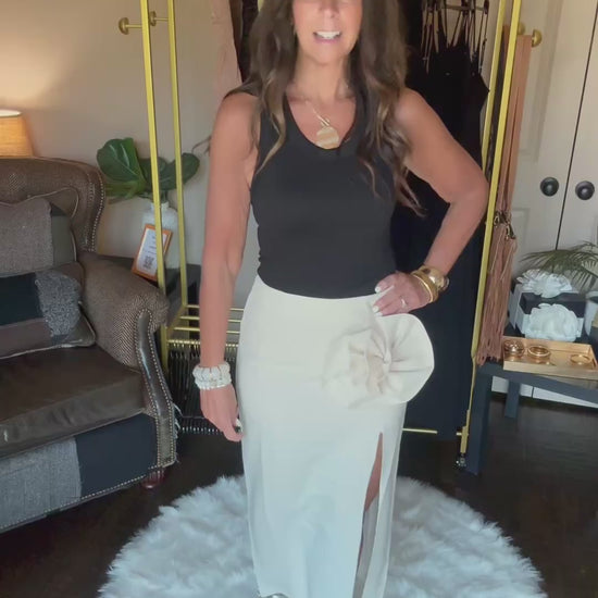 Woman modeling a long cream skirt in a home boutique.