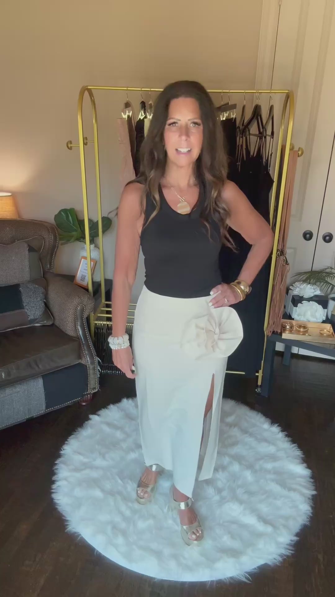 Woman modeling a long cream skirt in a home boutique.