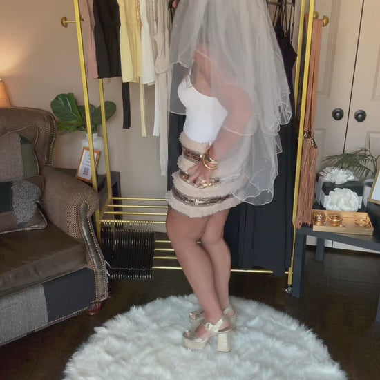 Video of a woman standing on a white rug in a room with clothing racks and furniture.
