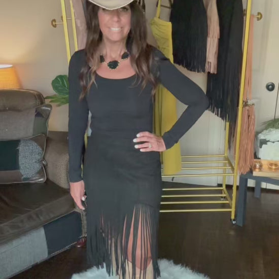 Woman modeling a black midi fringe skirt in a home boutique.