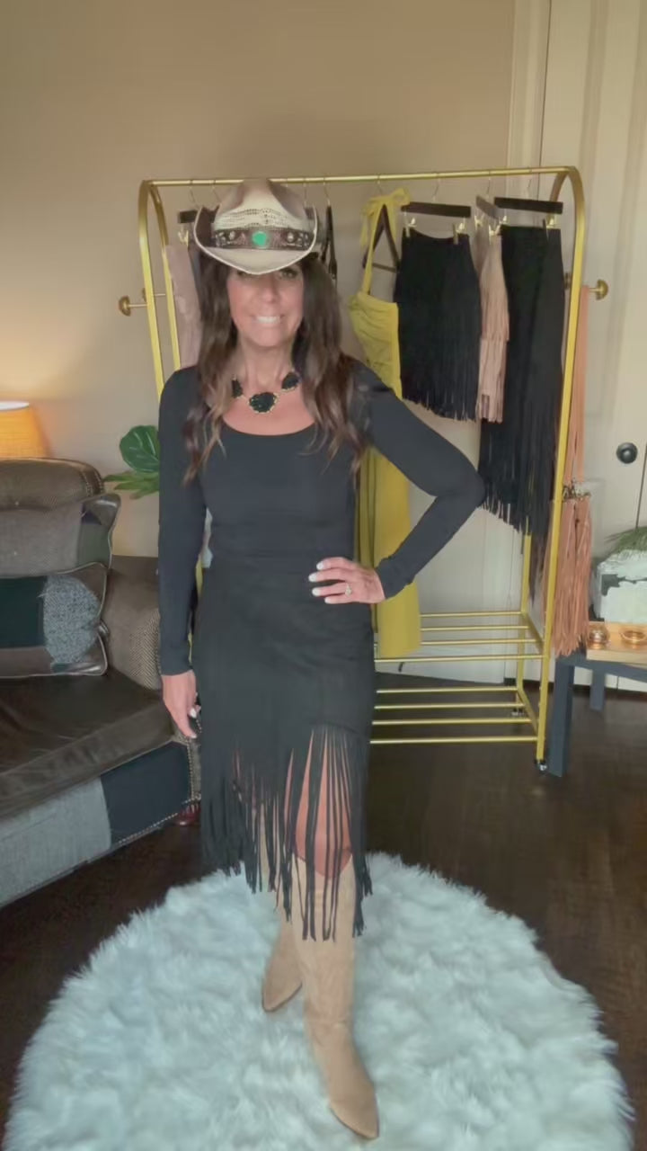 Woman modeling a black midi fringe skirt in a home boutique.
