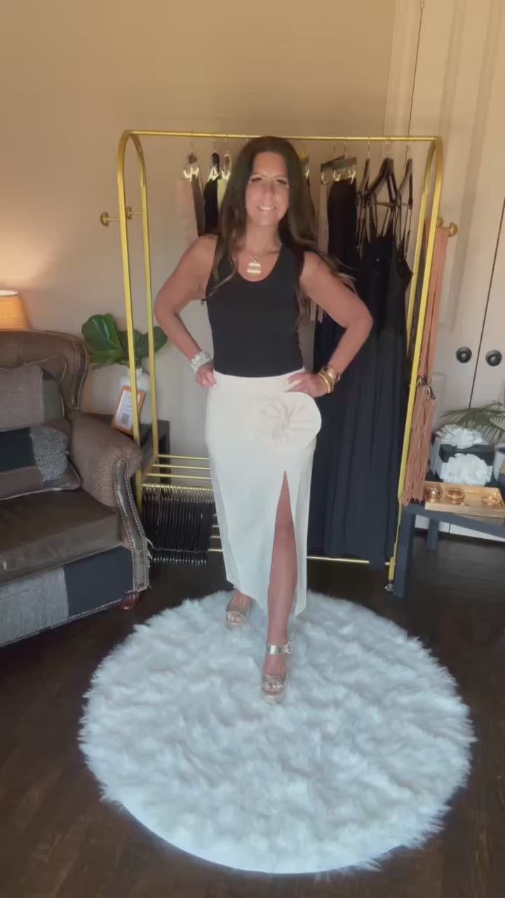 Woman modeling a long cream skirt in a home boutique.